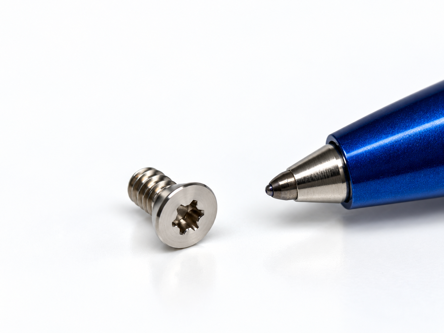 Vis miniature à empreinte Torx en inox, présentée près d’une pointe de stylo.